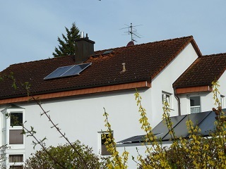 Eine solar-pac Schrägdachanlage auf Frankfurter Pfanne mit zwei Modulen und auf dem Flachdachvorbau ein weiteres Solarpanel.